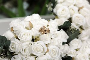 Closeup of elegant white rose bouquet with delicate petals and dark green foliage.