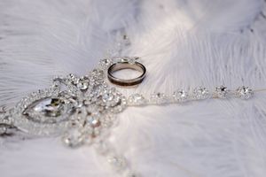 Crystal clear diamond wedding rings with small diamonds sparkling on white lace background and romantic lighting.