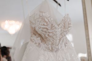 Three bridal gowns displayed on dress forms showcasing delicate lace details and intricate beading patterns.