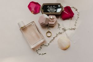 Delicate pink perfume bottles and rose petals arranged with crystal ornaments on a light surface.