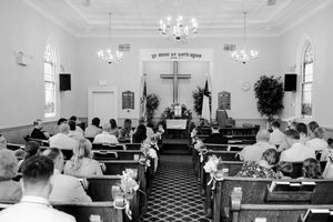 A church interior with people sitting in pews and empty seats during a service or gathering.