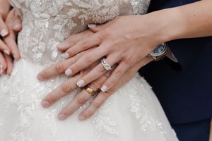 Close-up shots of hands wearing wedding rings and lace against dark background.