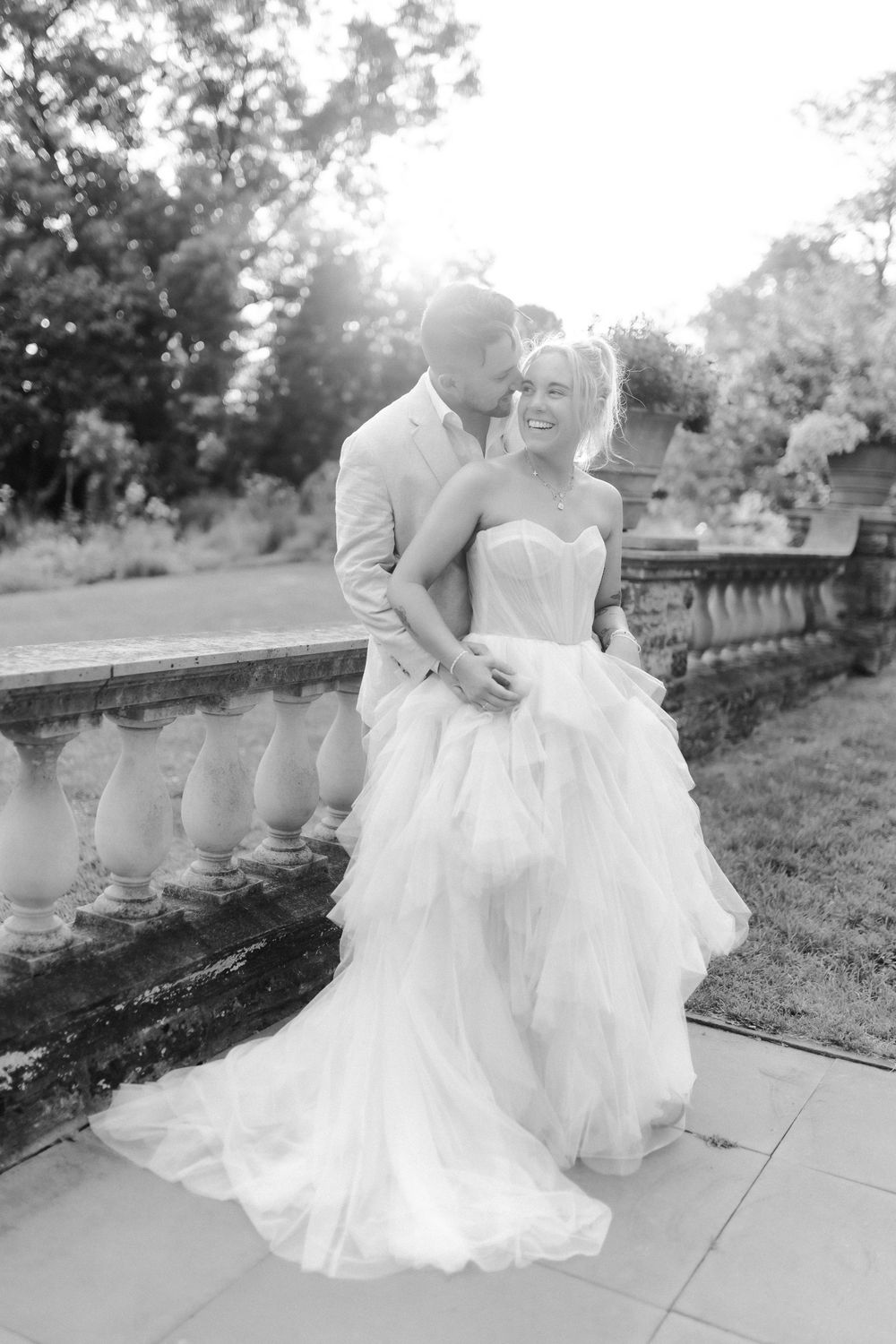 Romantic black and white wedding photo series showing a couple embracing on stone steps in natural sunlight.