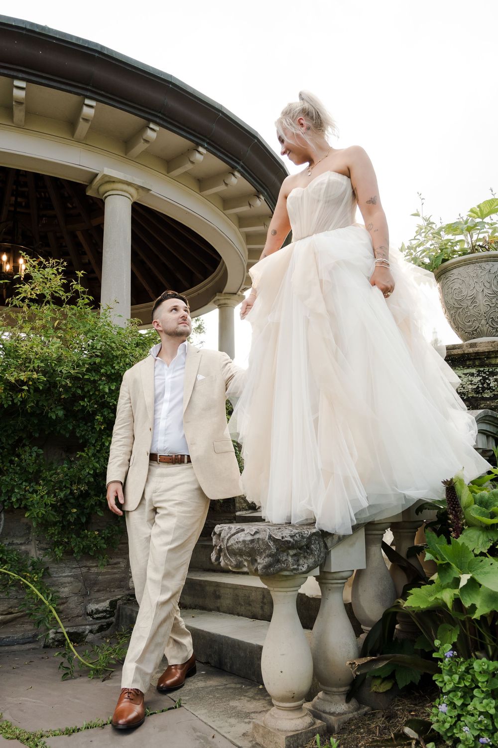A romantic moment captured at a garden pavilion with flowing white gown and light colored suit.