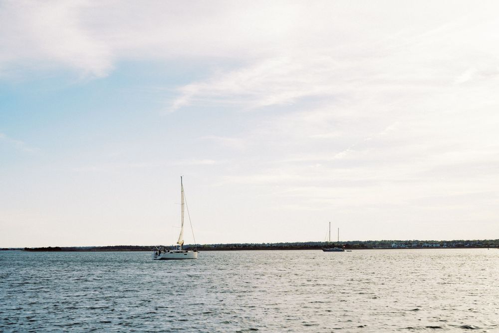 Tranquil seascape with sailboats anchored in calm waters under cloudy skies.