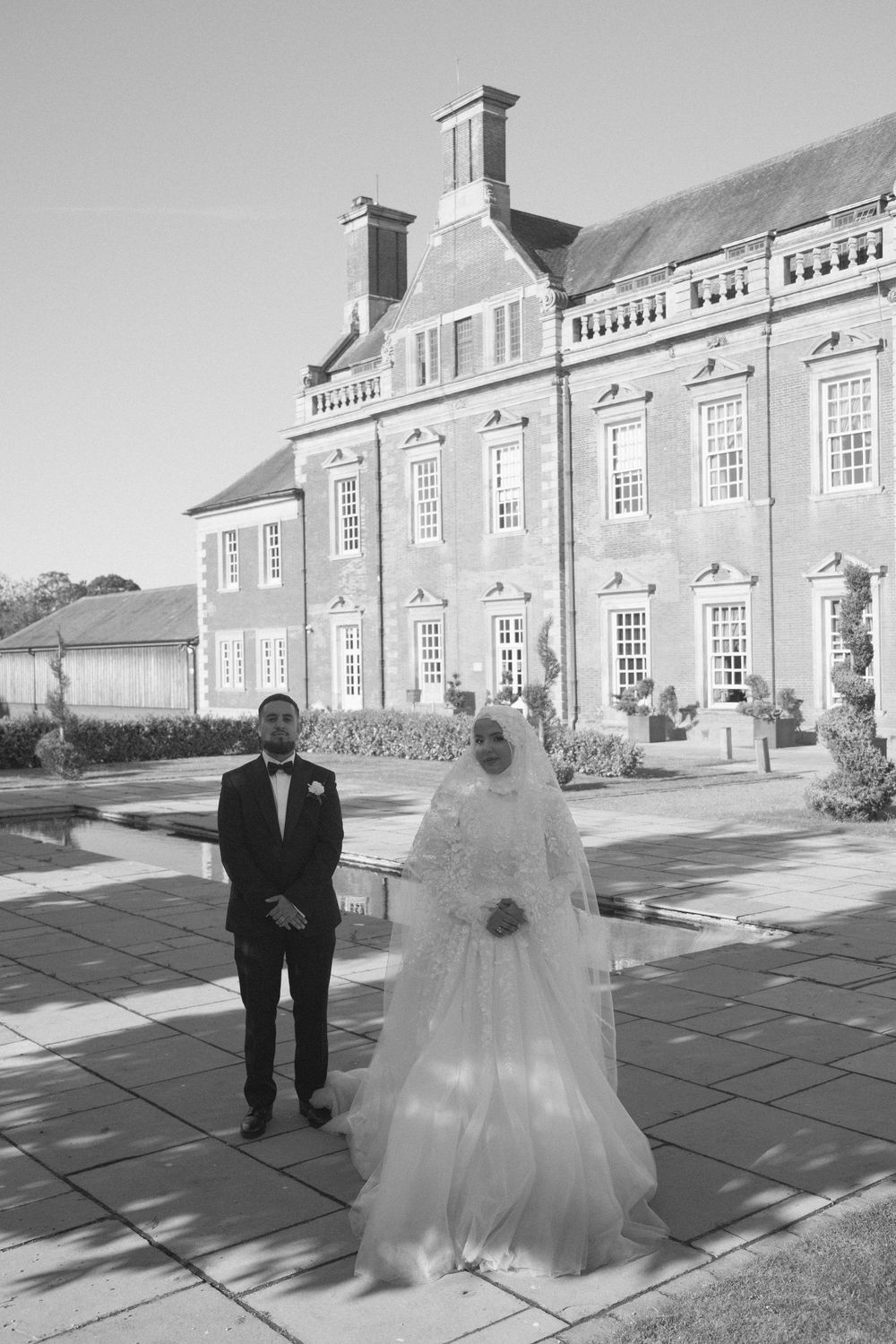 Wedding couple poses in front of a row of traditional Georgian style townhouses on a stone patio.