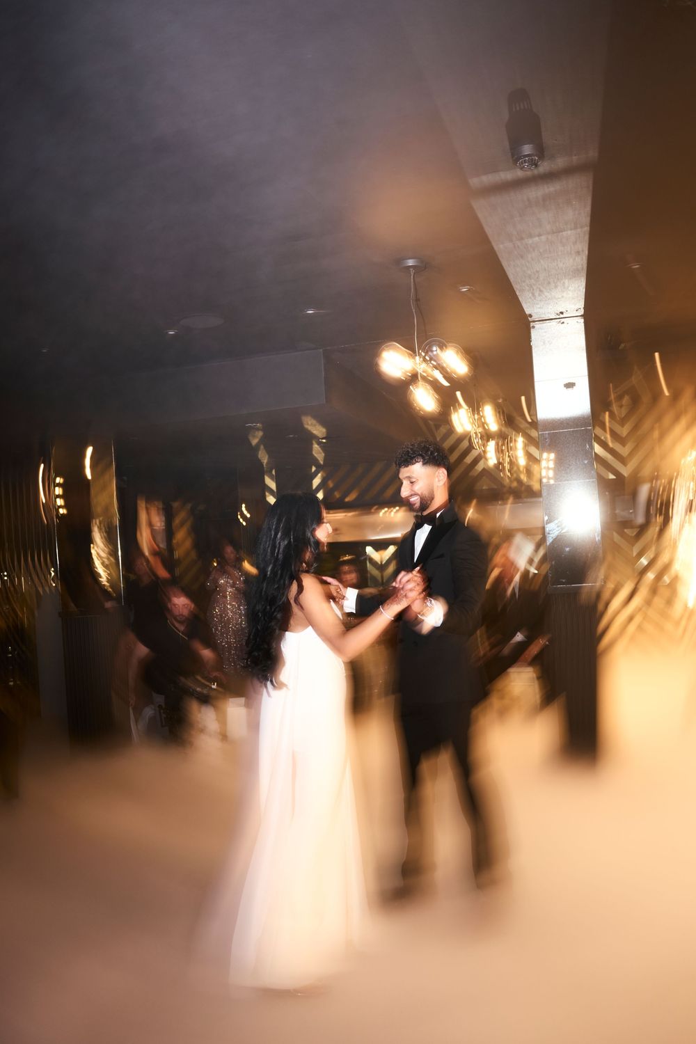 A romantic first dance at a wedding reception captured in motion blur with warm lighting.
