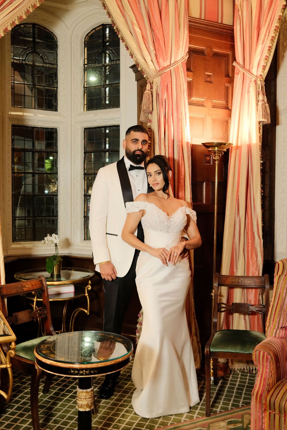 An elegant ballroom with pink striped curtains and vintage decor sets the scene for a romantic moment.