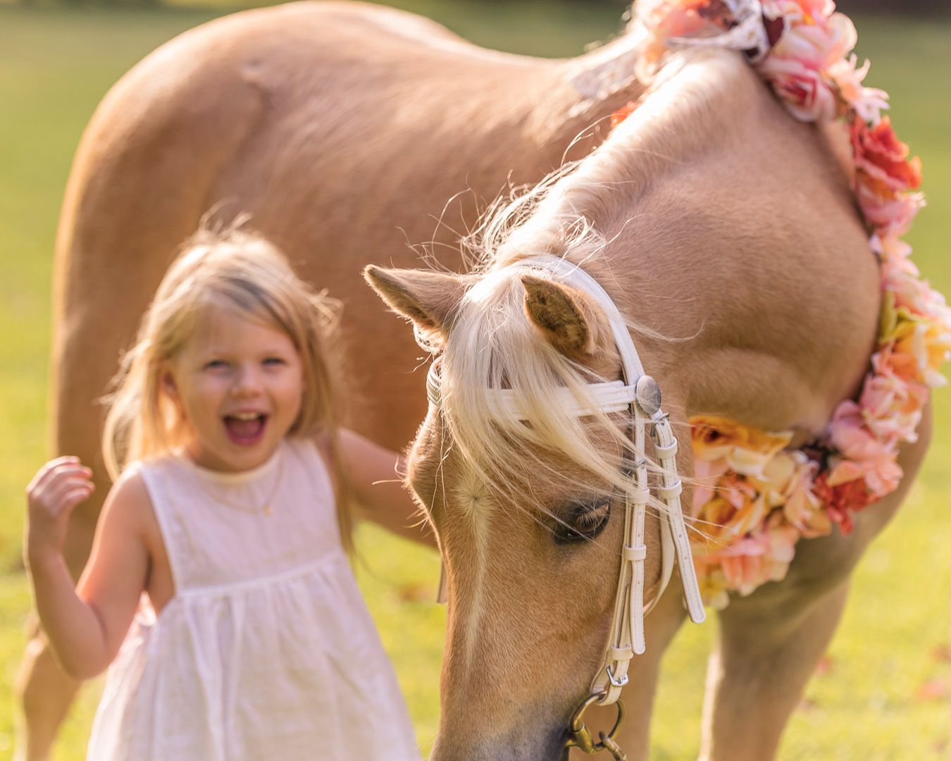 Joyful outdoor moment captured with flowing white dresses and floral decorations near a horse.