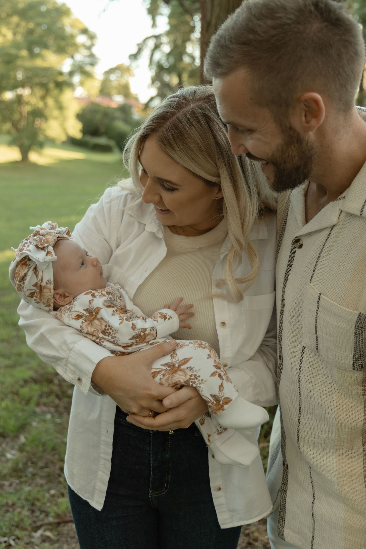 A tender family moment with a newborn baby outdoors in soft natural lighting.