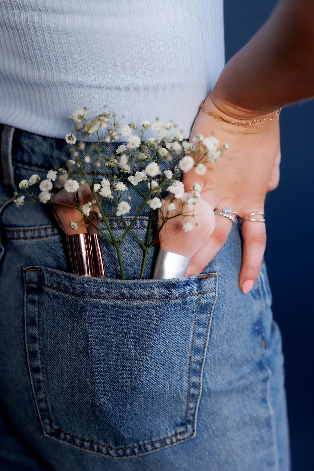Close-up of jean pocket containing baby's breath flowers and makeup brushes.