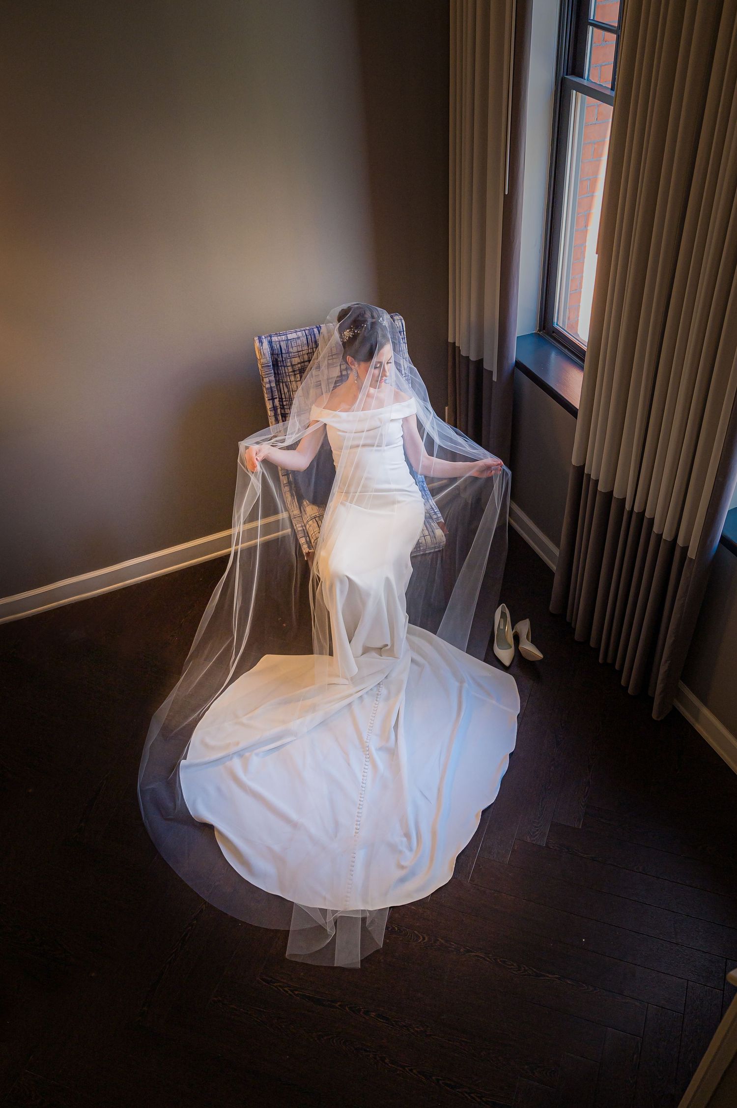 A ghostly white dress or fabric swirls against a dark background in a moody room creating an ethereal display.