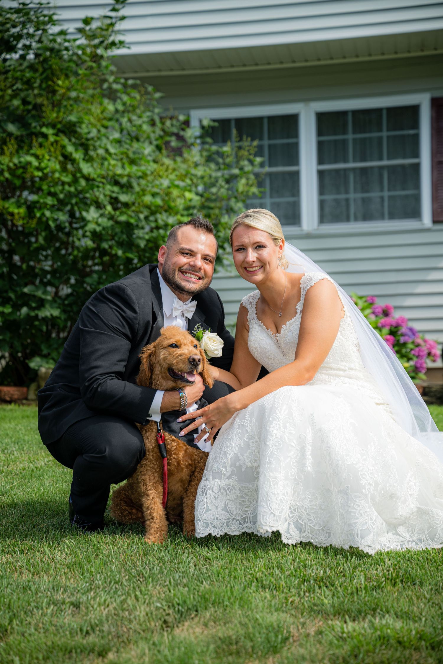 BRIDE AND GROOM WITH THEIR DOG IN THE MIDDLE.