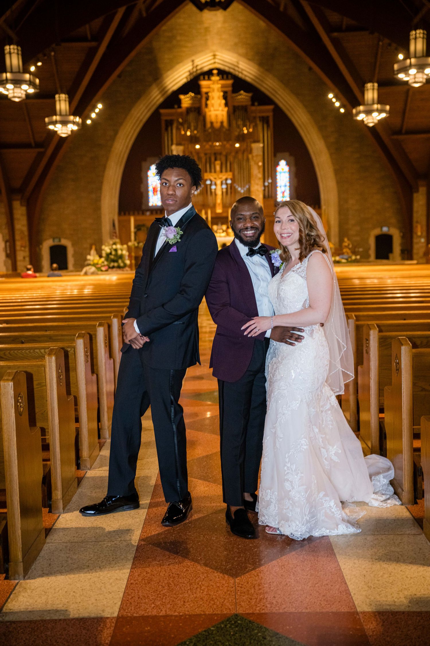 Wedding party members laugh together inside a grand cathedral with ornate arched ceilings and warm lighting.
