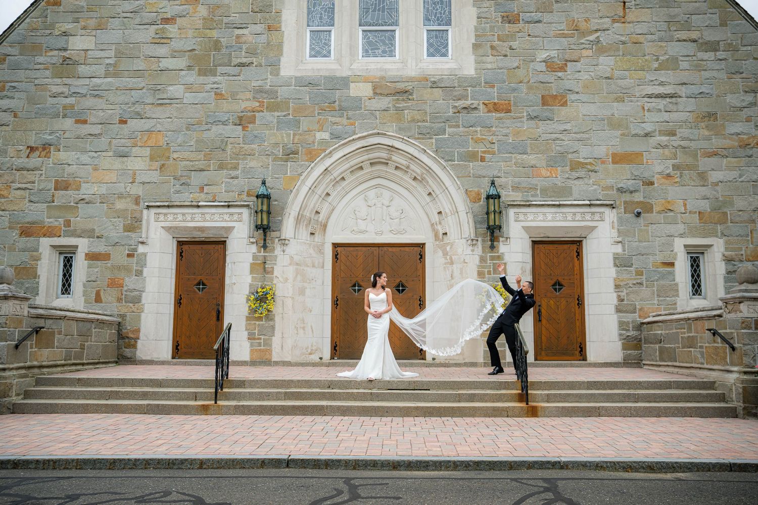 Stone church facade with multiple wooden doors and stone steps leading to a raised entrance platform.