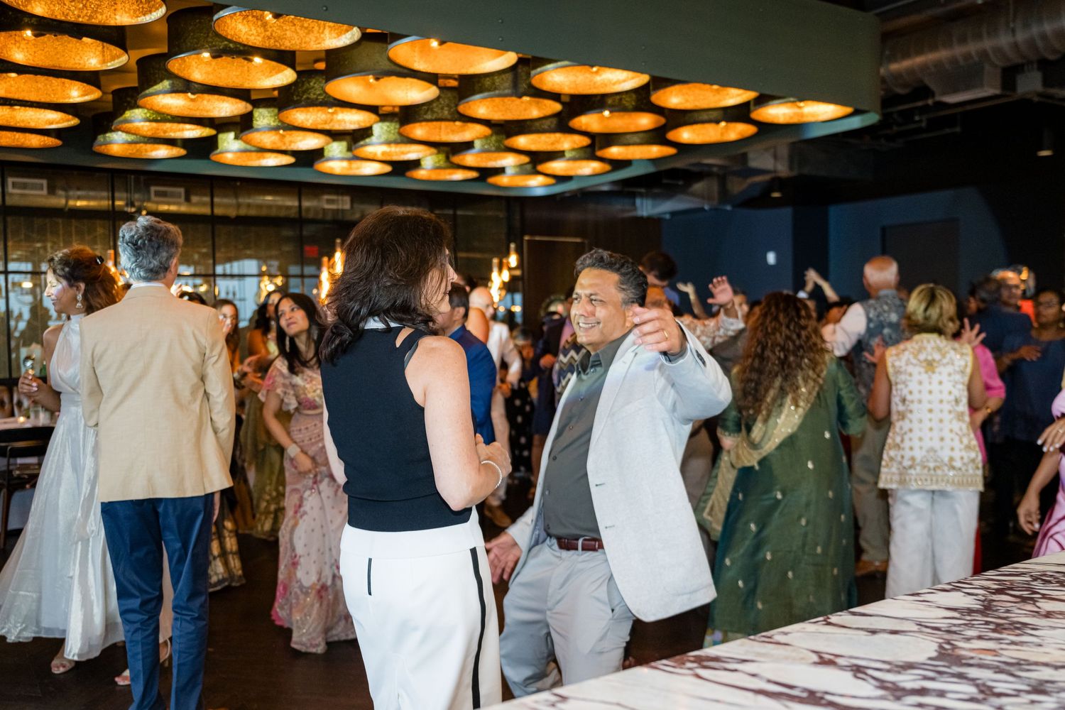 A collage of event photos showing people mingling and gathering at a formal indoor celebration with warm lighting fixtures.