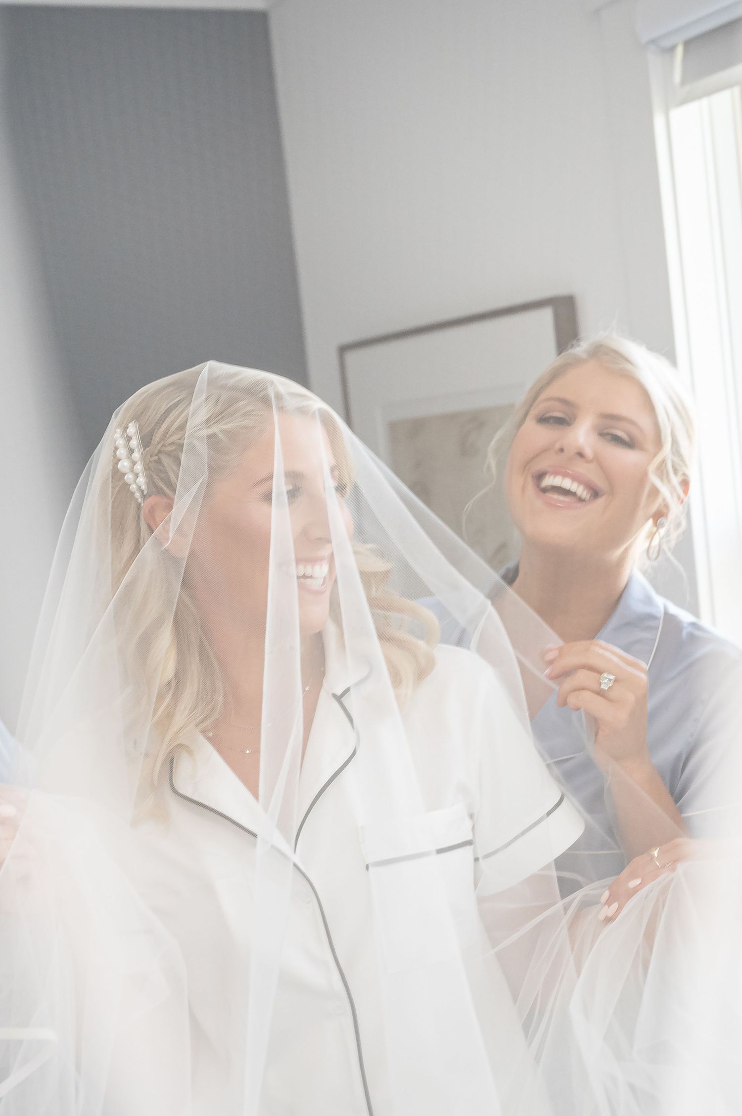 Happy moments captured through delicate white tulle veil during wedding preparations.