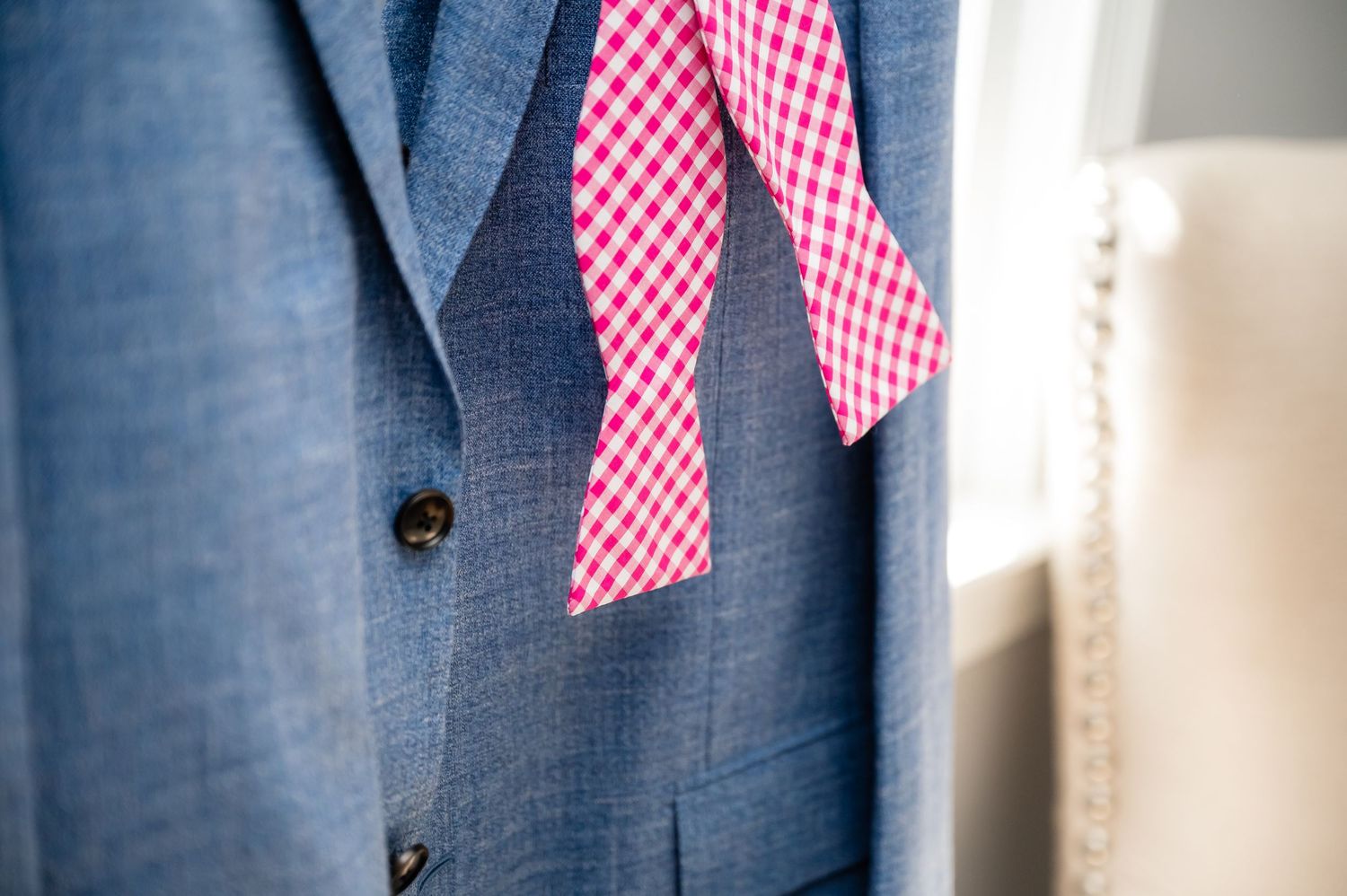 A blue denim jacket hangs on display with red and white gingham bowties attached for decoration.