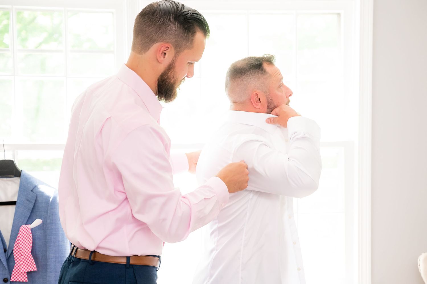 People in business attire having a discussion and greeting each other in a bright office environment.