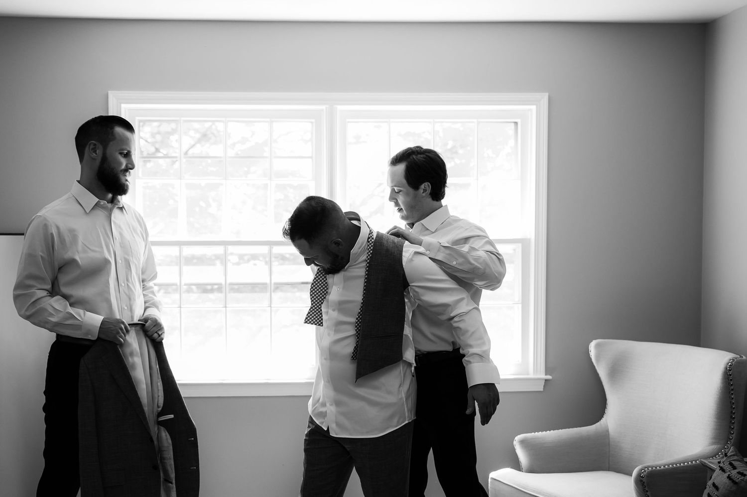 Two figures appear in silhouetted conversation near a window in a bright, minimalist office setting.