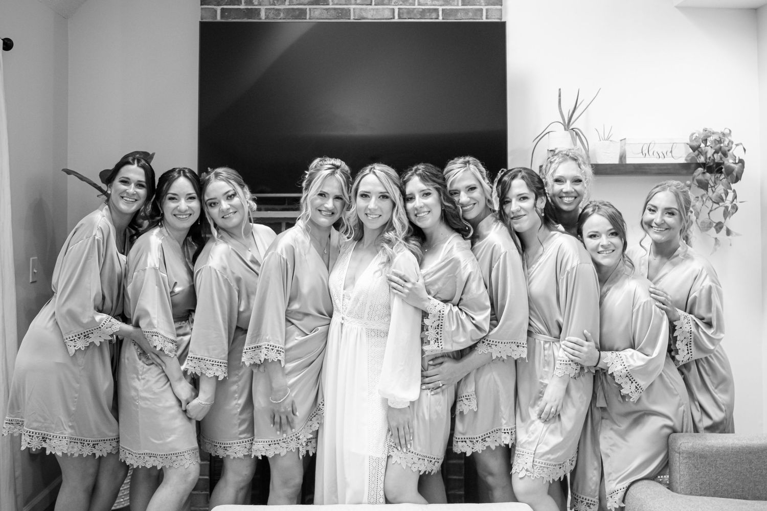A row of bridesmaids in matching gray robes pose together while getting ready for a wedding celebration.