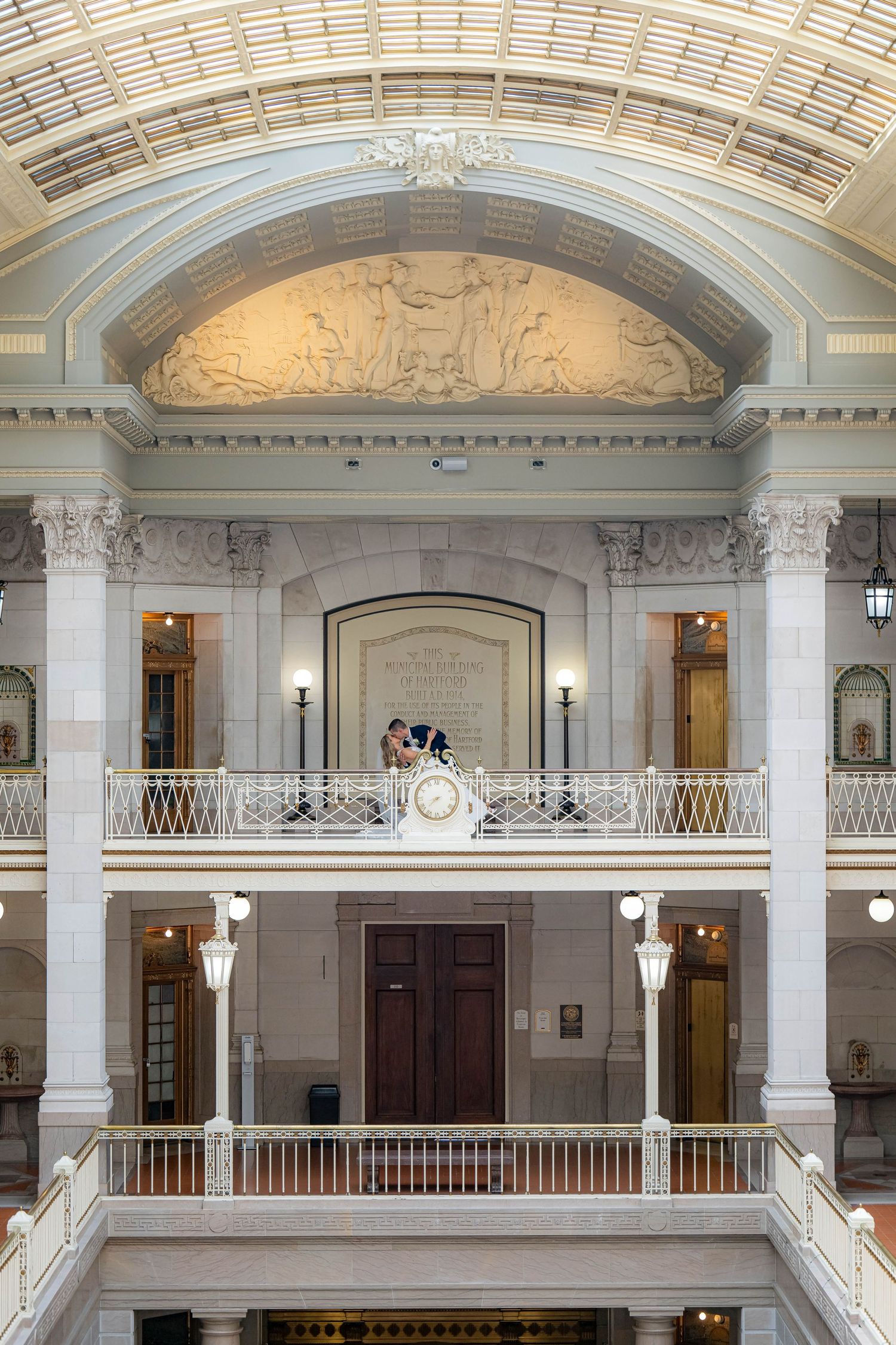 Ornate neoclassical interior architecture with white marble columns, arched ceilings, and decorative balustrades in a grand hallway.