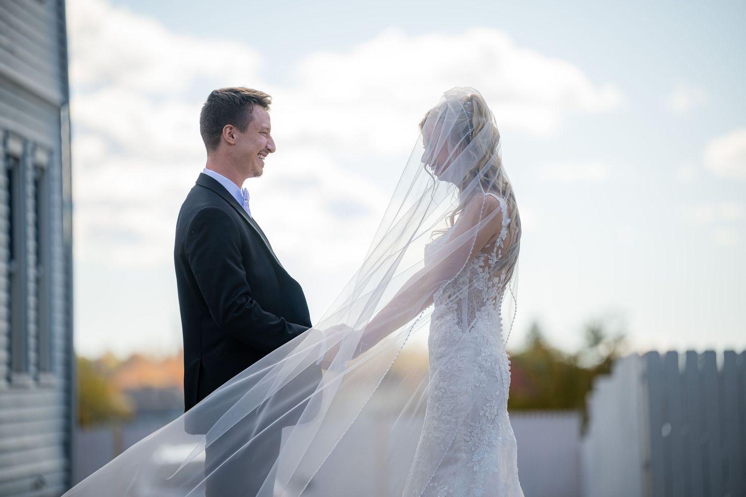 A couple in wedding attire stands together outdoors during their romantic first look moment.