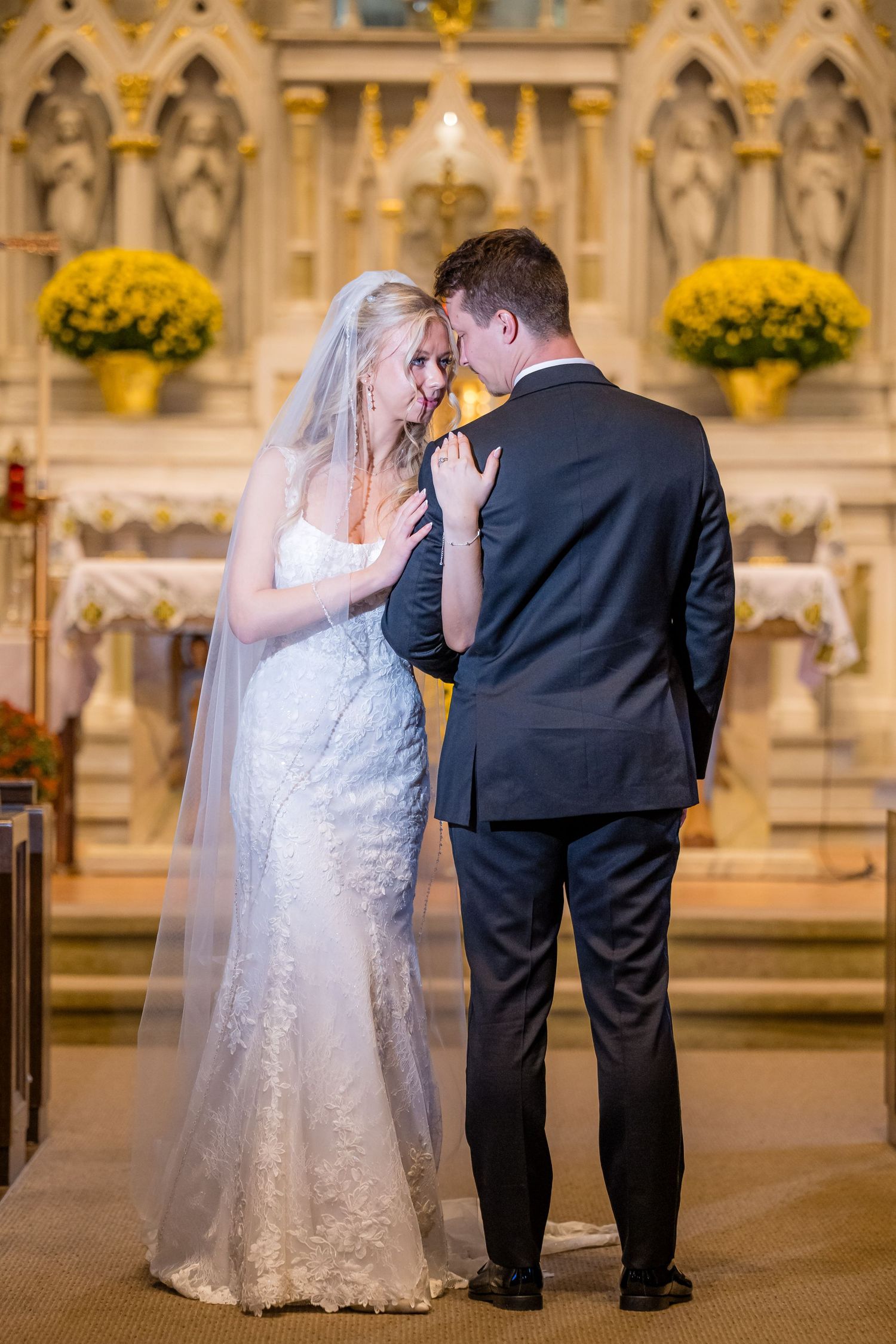 Elegant wedding couple shares intimate dance moments in a cathedral with yellow floral decorations.