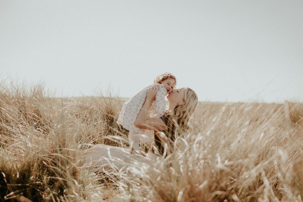 A couple embraces in a sun-drenched field of tall golden grass during a romantic outdoor photoshoot.