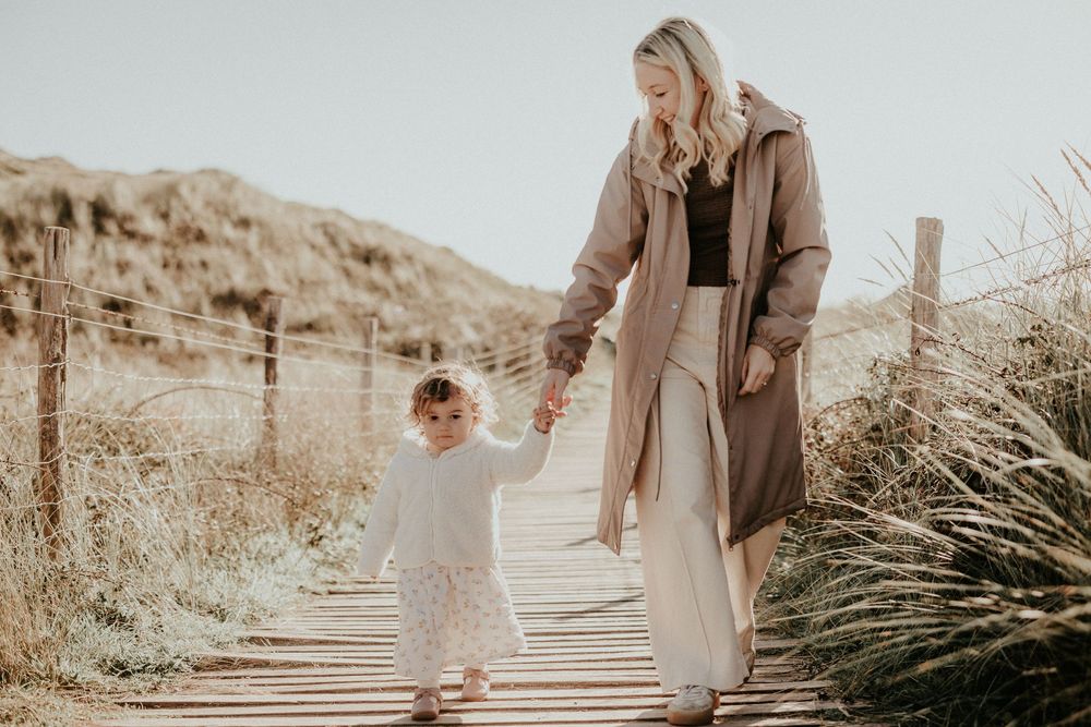 Sepia-toned photo series showing person in beige coat walking along wooden path in natural outdoor setting.