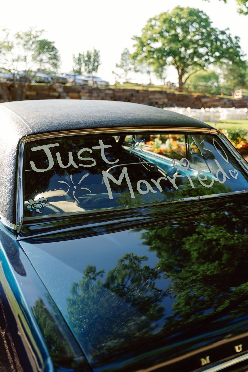 Writing on a car window in white paint with trees reflecting in the background.