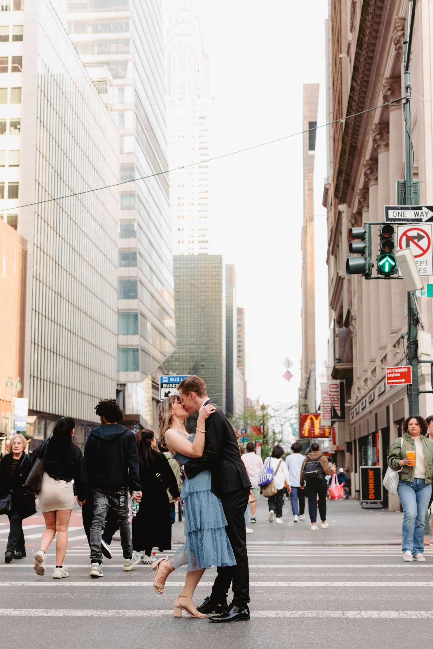 Couple dancing and embracing on a city street with tall buildings in background.