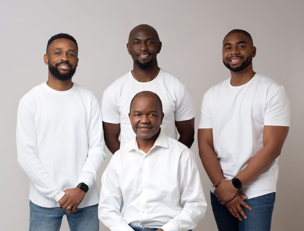A father with his sons wearing matching white t-shirts and jeans pose together in a studio photoshoot setting.