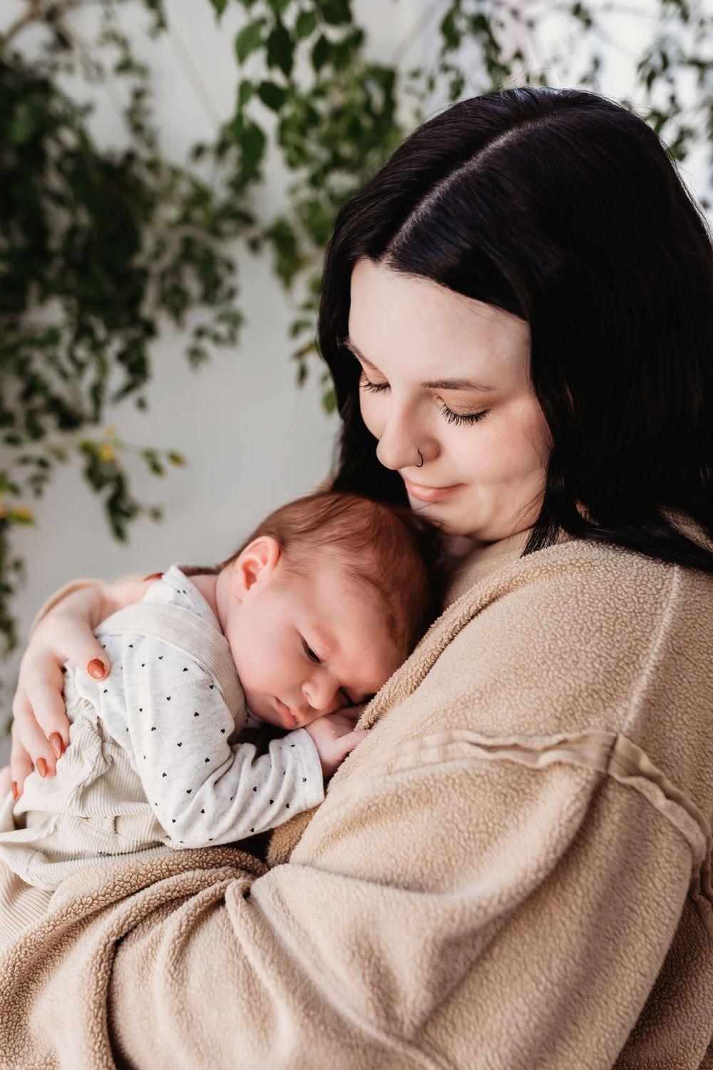 A tender moment captured as a baby sleeps peacefully against a caregiver wearing a cozy beige sweater.