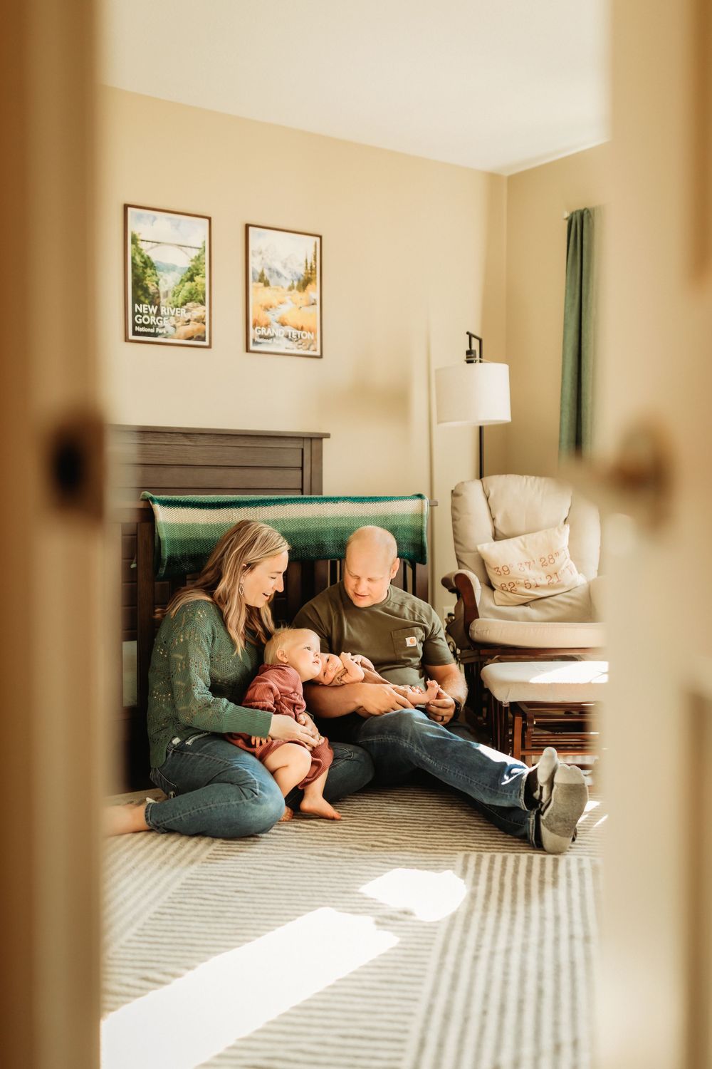 A cozy family moment in a bedroom with warm lighting and framed artwork on the wall as sunlight streams through the doorway.