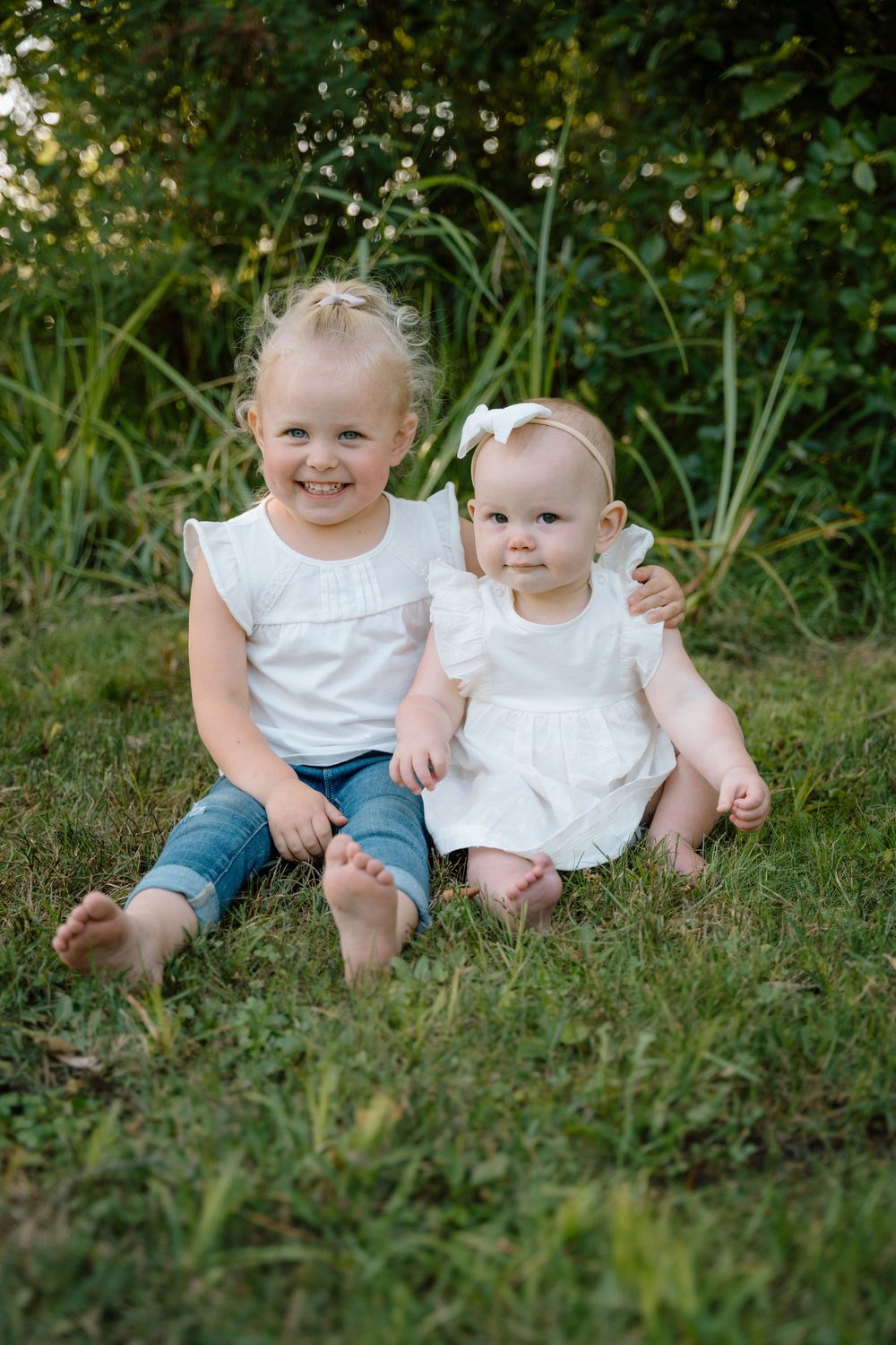 Children sit together on grass for a casual outdoor portrait session.