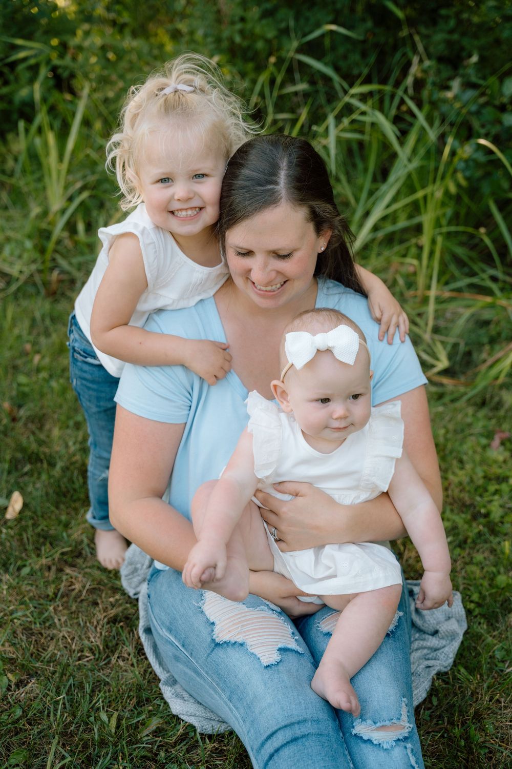A sweet outdoor portrait session in a grassy area with natural greenery in the background.