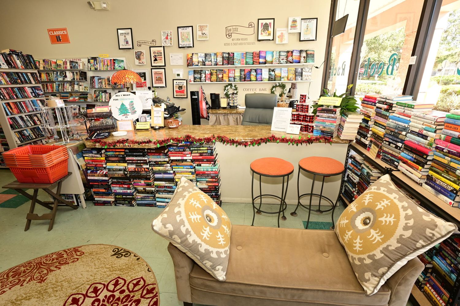 Interior view of a cozy used bookstore with orange chairs, decorative pillows, and bookshelves lining the walls.
