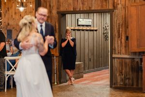 Wedding guests holding up sparklers create a glowing archway tunnel outside a rustic wooden barn at night.
