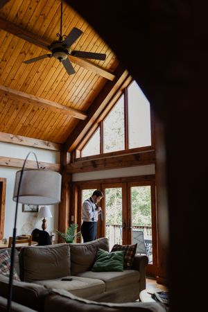 Cozy A-frame cabin interior with wooden beams, vaulted ceiling, and large windows overlooking nature.