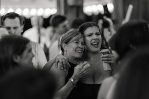 A black and white photograph shows a group of people laughing and smiling together at a social gathering.