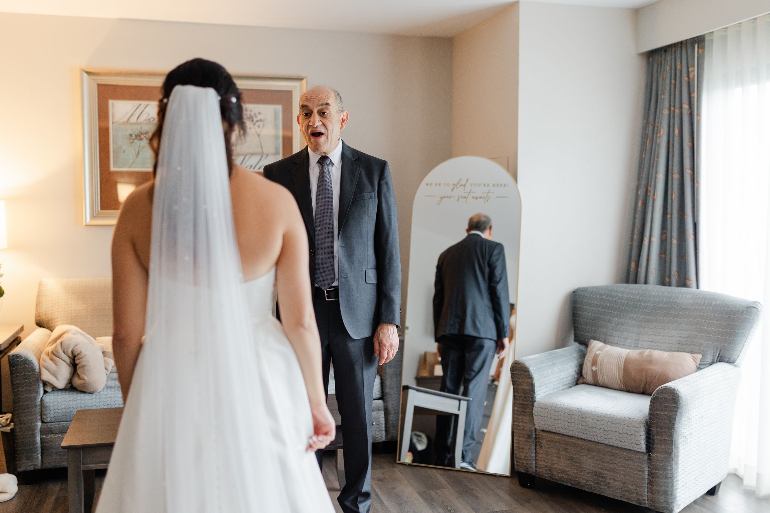 A touching pre-wedding moment captured in a hotel room with light streaming through windows.