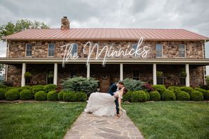 A rustic stone venue with red metal roof and manicured landscaping features The Merricks signage on its facade.