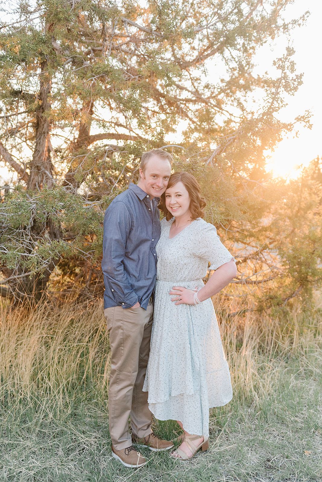 A couple poses together in a romantic sunset photoshoot with golden light filtering through trees.