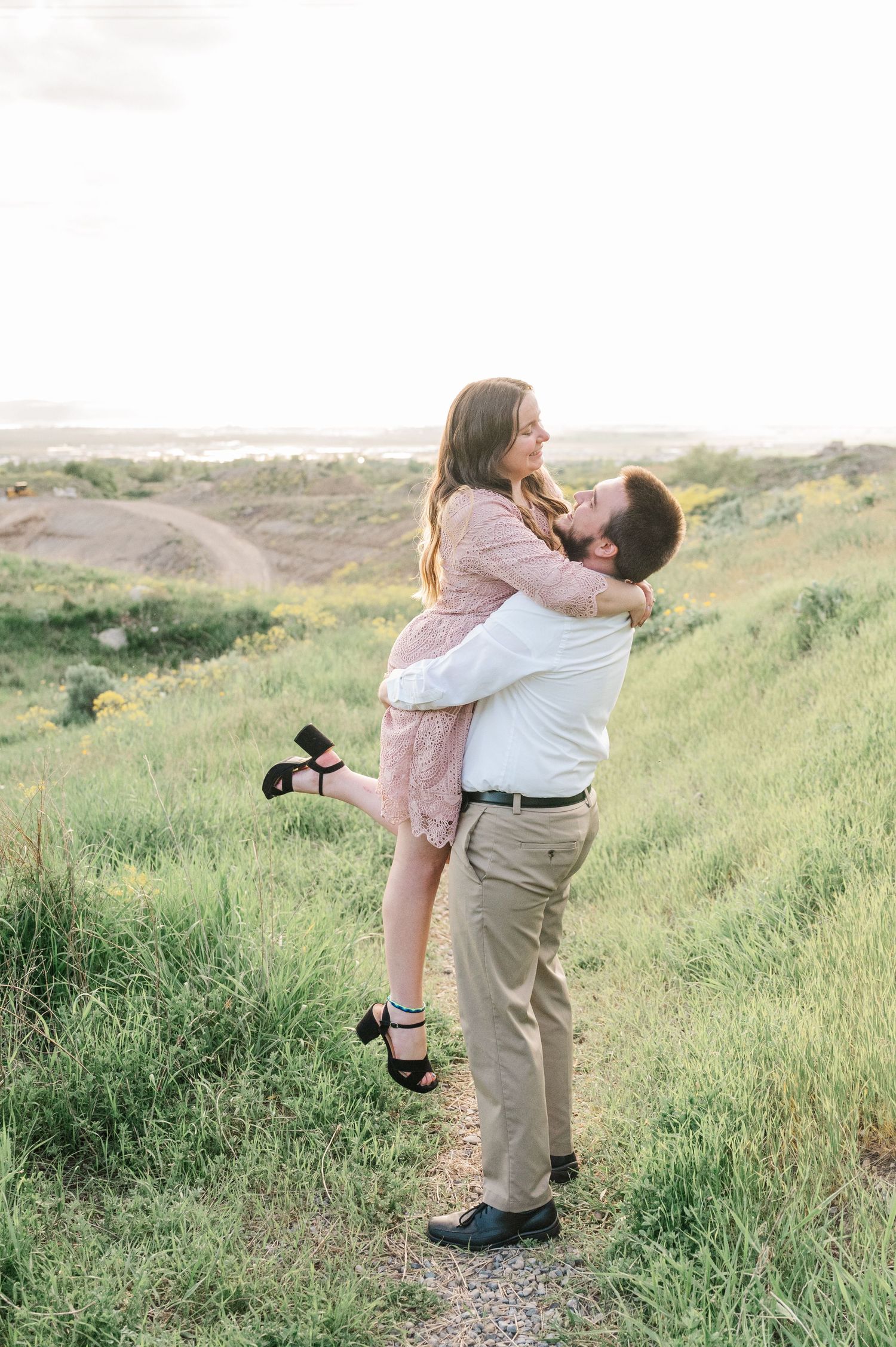 Romantic embrace on hillside path during sunset photoshoot.