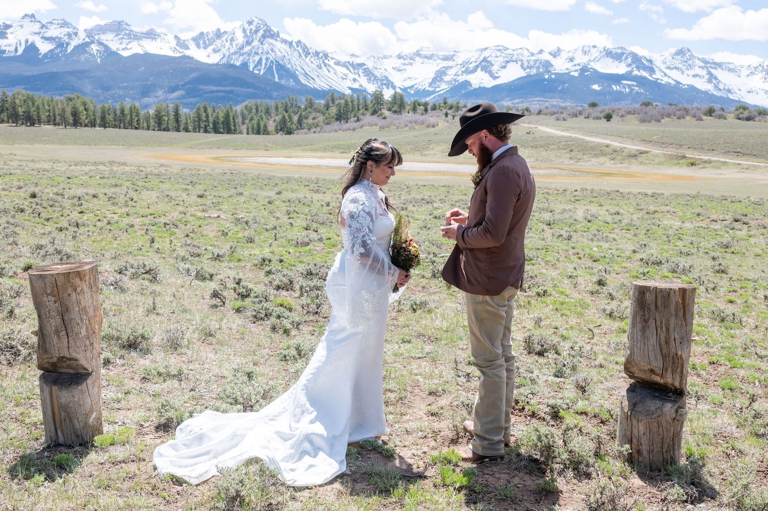 An eloping couple sitting by a lake near Breckenridge, Colorado, sharing wedding cake and champagne with mountain scenery behind them.