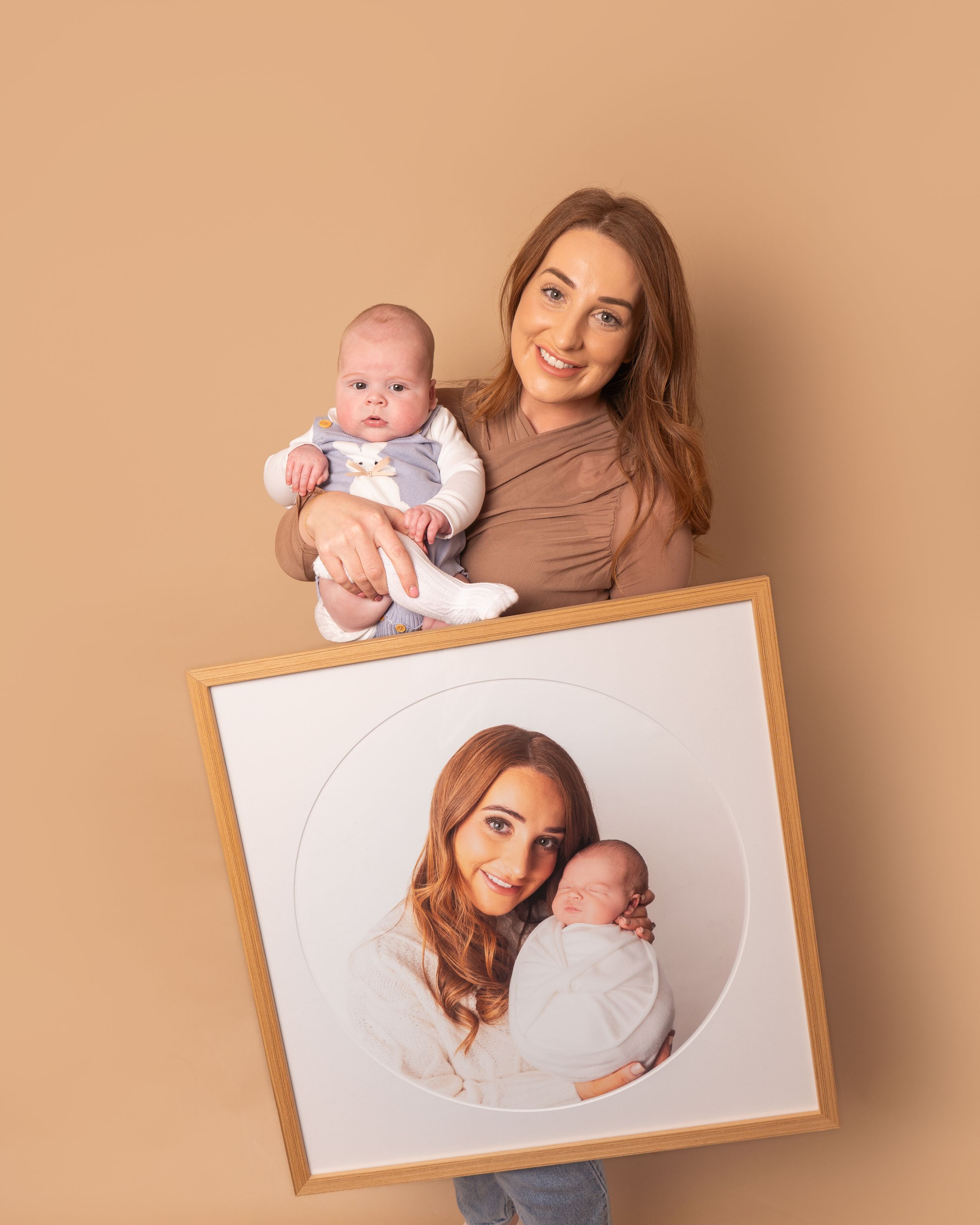 client holding baby boy and large wall art frame with photo from newborn session by newborn photographer in Doncaster.