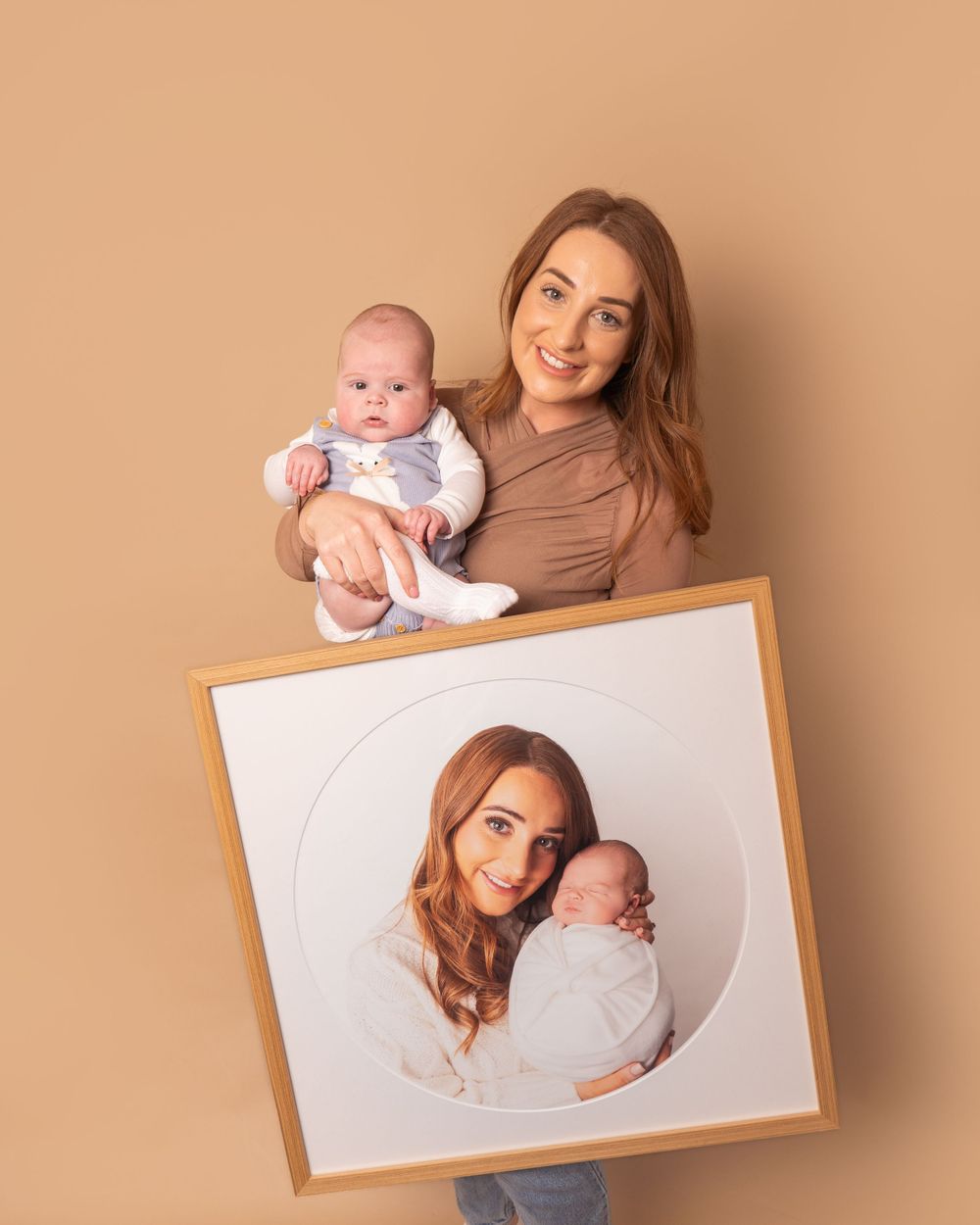 client holding baby boy and large wall art frame with photo from newborn session by newborn photographer in Doncaster.