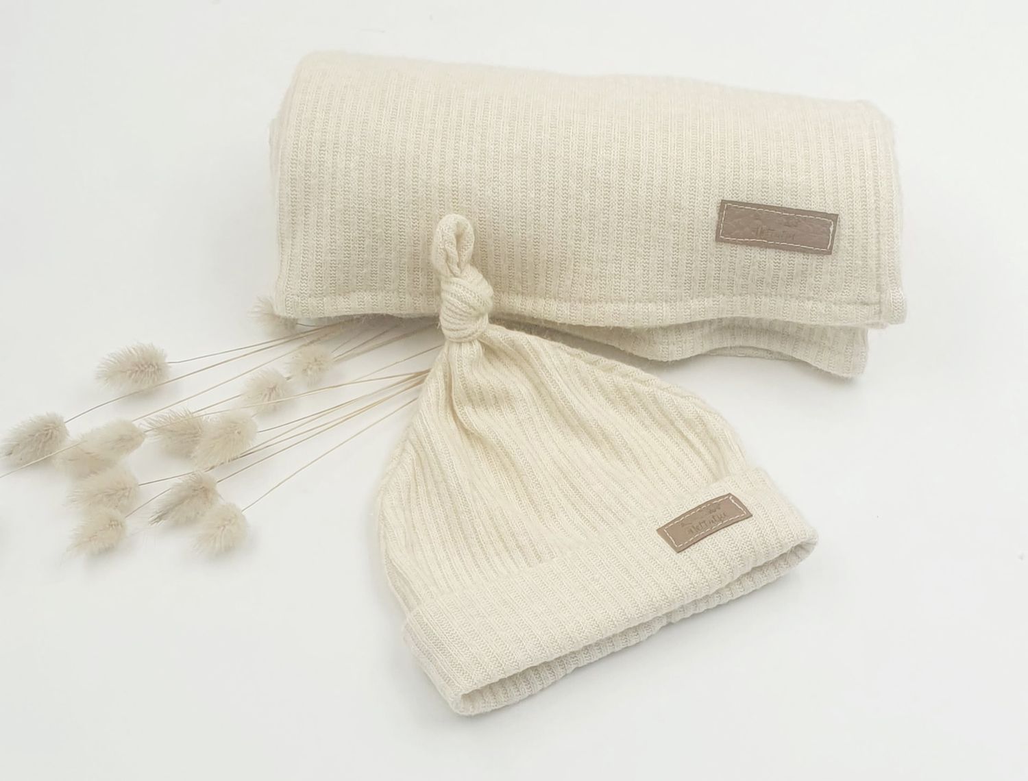 Cream colored knit baby blanket with brown leather label detail.