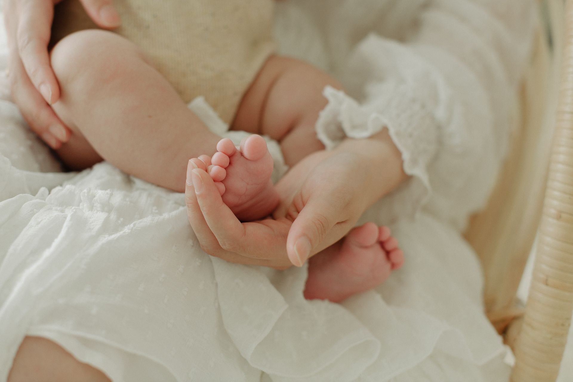 Close-up of tiny baby feet being gently held in white fabric.